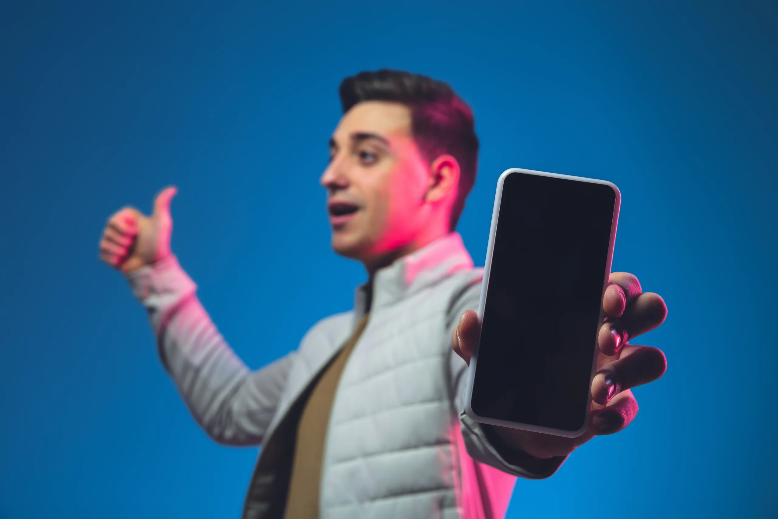 A man holding a smartphone with a blank screen, giving a thumbs-up gesture against a blue background. Best Top 5 Smartphones ₹50,000